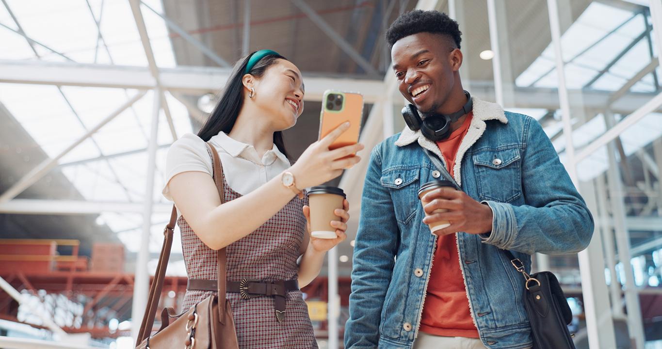 Deux étudiants souriants regardant leur téléphone portable, ce qui représente les solutions d'apprentissage linguistique de Rosetta Stone pour les écoles qui encouragent l'interactivité et l'apprentissage mobile.